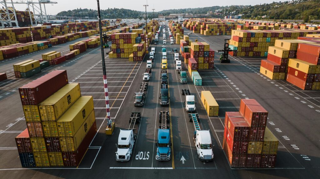 A bustling aerial shot of Seattle's shipping port with trucks lined up amongst colorful cargo containers.